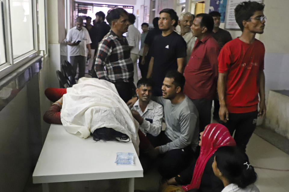 Relatives mourn next to a body lying covered at the Sikandrarao hospital in Hathras district about 350 kilometers (217 miles) southwest of Lucknow, India, Tuesday, July 2, 2024. A stampede among thousands of people at a religious gathering in northern India has killed at least 105 and left scores injured, officials said Tuesday, with many women and children among the dead. (AP Photo/Manoj Aligadi)