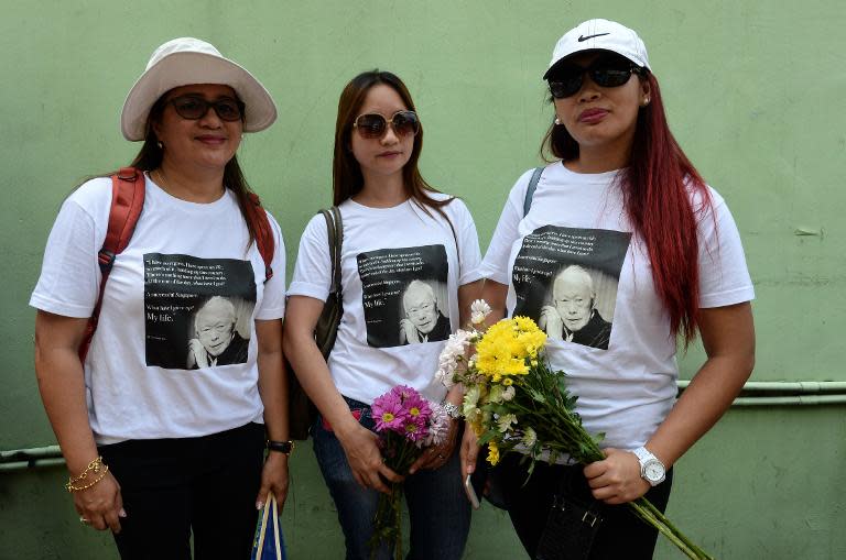 Three women pose for a photo while queuing to pay their respects to Singapore's late former prime minister Lee Kuan Yew, outside Parliament House, on March 25, 2015