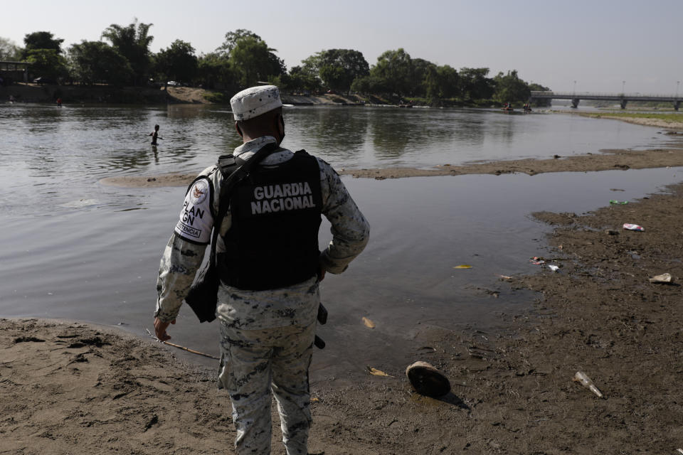 A Mexican National Guard stands on the bank of the Suchiate River, the natural border with Guatemala and Mexico, near Ciudad Hidalgo, Mexico, Sunday, March 21, 2021. Mexico has sent hundreds of immigration agents, police and National Guard to its southern border to launch an operation to crack down on migrant smuggling. (AP Photo/Eduardo Verdugo)