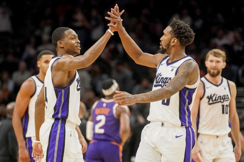 Sacramento Kings' De'Aaron Fox, left, and Malik Monk, right, high-five as the Kings led by 14 during the second half of the team's NBA basketball game against the Phoenix Suns on Friday, Dec. 8, 2023, in Phoenix. (AP Photo/Darryl Webb)