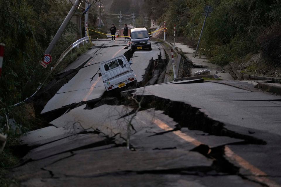 Bystanders look at damages somewhere near Noto town in the Noto peninsula facing the Sea of Japan, northwest of Tokyo, Tuesday, Jan. 2, 2024, following Monday's deadly earthquake. A series of powerful earthquakes that hit western Japan have damaged thousands of buildings, vehicles and boats. Officials warned that more quakes could lie ahead.