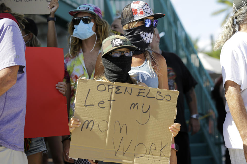 Bartender Kat DeLaTorre stands with her son Nico, 12, during a "Right to Work" rally outside of the Elbo Room bar, which remains closed, during the new coronavirus pandemic, Tuesday, June 16, 2020, in Fort Lauderdale, Fla. Across Florida, bars were part of the Phase 2 reopenings that occurred earlier in June, except in three counties in South Florida. (AP Photo/Lynne Sladky)