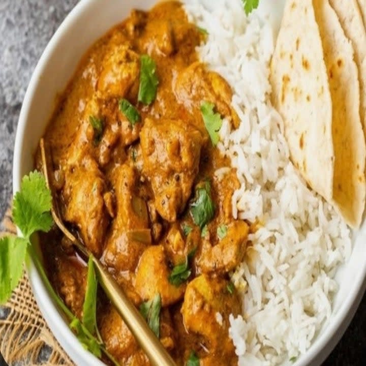 pumpkin curry in a bowl with rice and naan