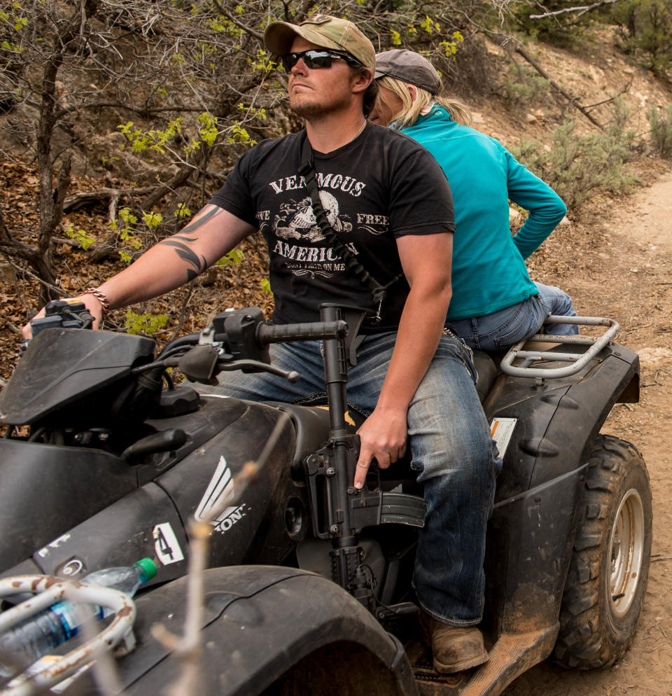 An ATV rider holds his finger near the trigger of his assault rifle as he and others make their way into Recapture Canyon, north of Blanding, Utah, on Saturday, May 10, 2014, in a protest against what demonstrators call the federal government's overreaching control of public lands. The area has been closed to motorized use since 2007 when an illegal trail was found that cuts through Ancestral Puebloan ruins. The canyon is open to hikers and horseback riders. (AP Photo/The Salt Lake Tribune, Trent Nelson)