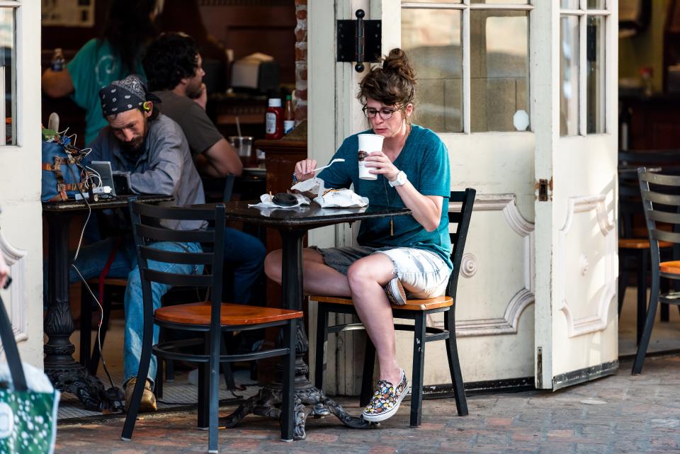 Woman drinking coffee at cafe, sitting in outdoor table in New Orleans, Louisiana.