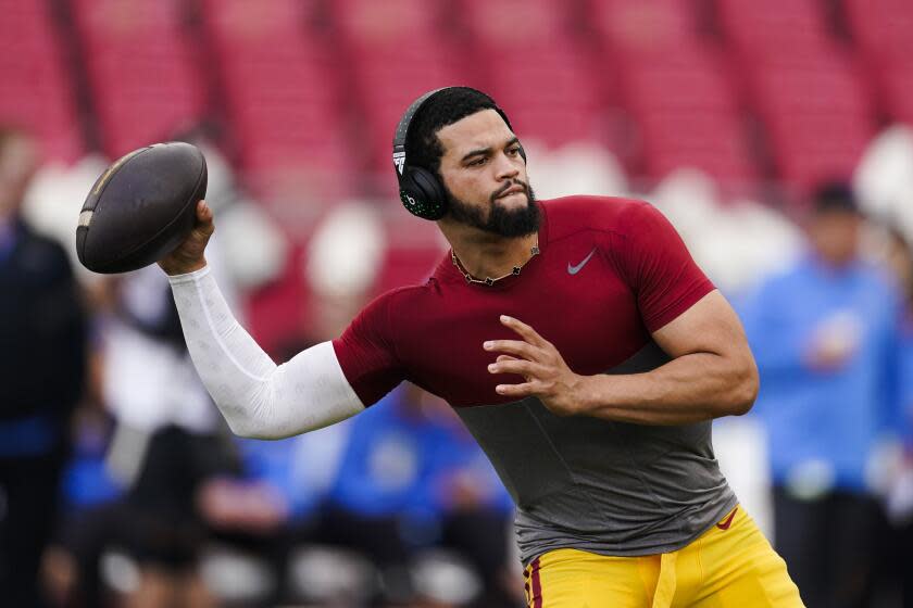 USC quarterback Caleb Williams wears earphones and looks to sling the ball with his right hand as warms up for a game.