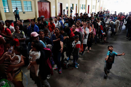 Honduran migrants, part of a caravan trying to reach the U.S., queue to get a mat to rest at a migrant shelter in Guatemala City, Guatemala October 17, 2018. REUTERS/Luis Echeverria