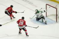 Chicago Blackhawks' Dylan Strome, left, scores past Dallas Stars goaltender Jake Oettinger, right, off an assist from Vinnie Hinostroza, center, during the second period of an NHL hockey game Monday, May 10, 2021, in Chicago. (AP Photo/Charles Rex Arbogast)