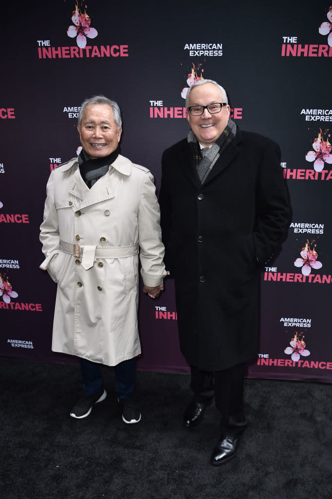 bundled up holding hands on a red carpet