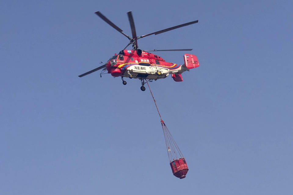 In this photo released by Xinhua News Agency, a fire-fighting helicopter leaves on a mission to fight aforest fire in the Muli County in Liangshan Yi Autonomous Prefecture from an airport in Xichang, southwest China's Sichuan Province, Monday, April 1, 2019. The fire high in the mountains of western China's Sichuan province has killed over two dozen firefighters and others, the government said Monday. (Lin Jiping/Xinhua via AP)