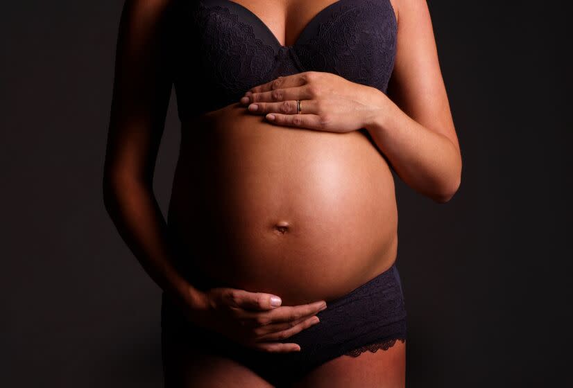 Close up of a pregnant lady's stomach, isolated - Hands on her stomach