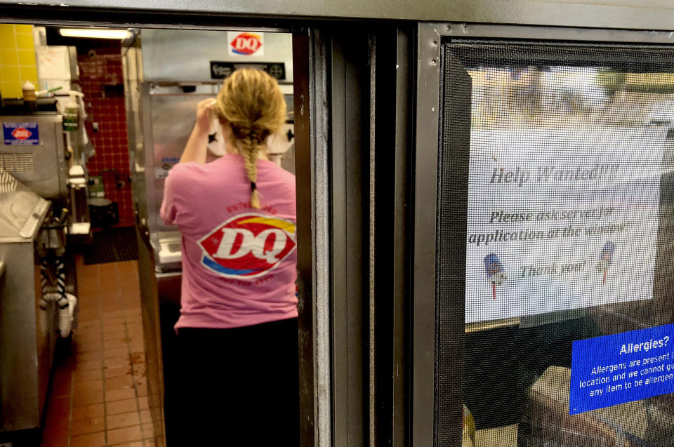 FILE - In this Sunday, Aug. 19, 2018, file photo a woman prepares a cup of ice cream behind a "Help Wanted" sign at a Dairy Queen fast food restaurant in Rutherford, N.J. On Tuesday, Sept. 11, the Labor Department reports on job openings and labor turnover for July. (AP Photo/Ted Shaffrey, File)