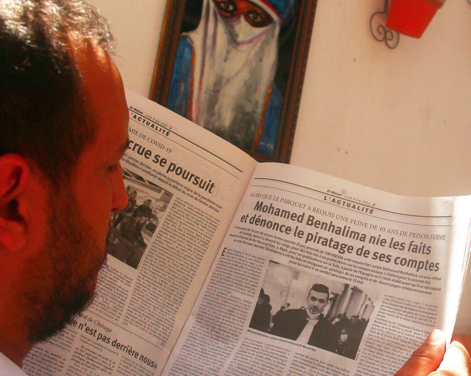 A man reads an article on Mohamed Benhalima in El Watan newspaper in Algiers Sunday, May 22, 2022. On March 24 2022 a team from Algeria's Rapid Intervention Force then puts him in their vehicle, strapping him with a protective vest before the ride to his still unknown destination, video on social media shows. (AP Photo/Fateh Guidoum)