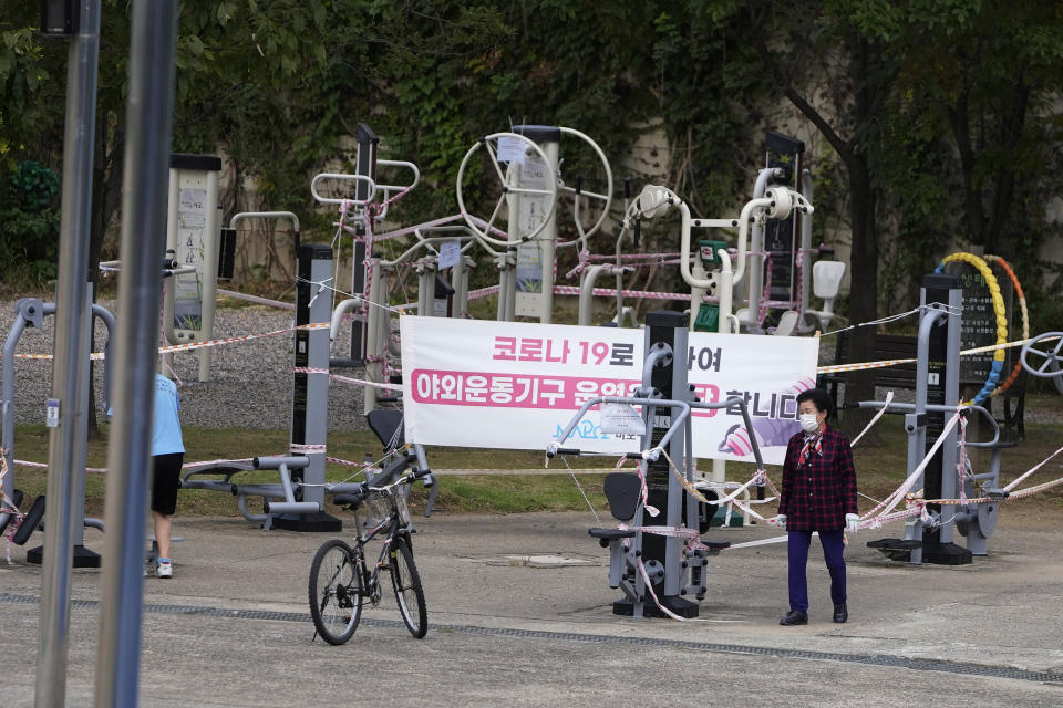 A woman walks near a public sports facilities area taped off as a precaution against the coronavirus in Seoul, South Korea, Thursday, Sept. 23, 2021. The letters read "Outdoor sports facilities are suspended due to COVID-19." (AP Photo/Lee Jin-man)