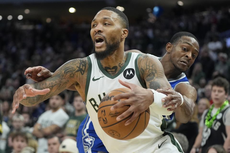 Milwaukee Bucks' Damian Lillard is fouled by Sacramento Kings' De'Aaron Fox during the second half of an NBA basketball game Sunday, Jan. 14, 2024, in Milwaukee. The Bucks won 143-142 in overtime. (AP Photo/Morry Gash)