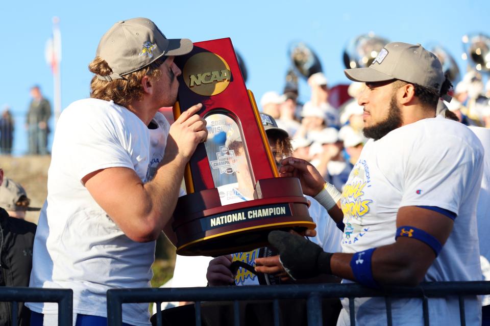 South Dakota State quarterback Mark Gronowski, left, kisses the trophy as Jason Freeman, right, waits to hold it after their win over Montana at the FCS Championship NCAA college football game Sunday, Jan. 7, 2024, in Frisco, Texas. (AP Photo/Richard W. Rodriguez)