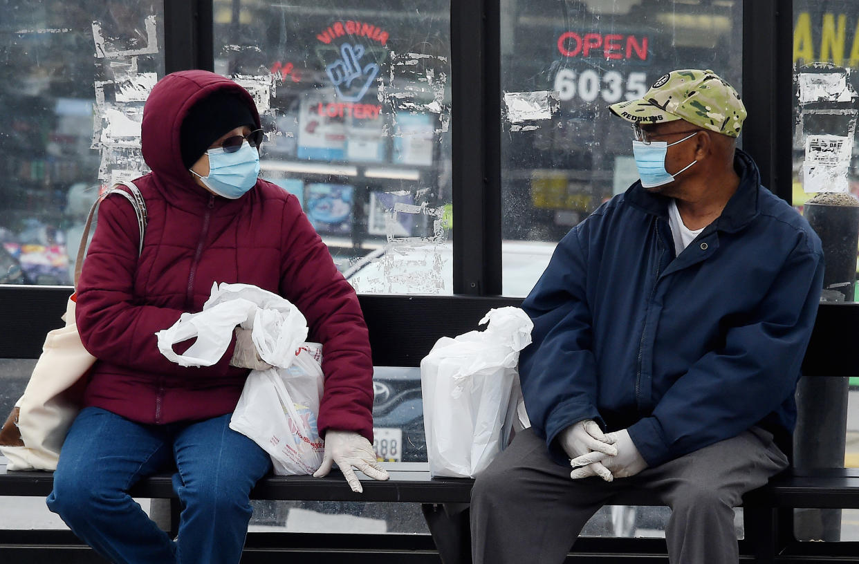 People wearing face masks wait for their bus amid the coronavirus pandemic on May 14, 2020 in Arlington, Virginia. - Over a third of US workers who lost jobs or saw their hours reduced because of the coronavirus pandemic will have trouble paying their bills and nearly half do not have an extra $400 for an emergency, according to a survey released Thursday. (Photo by Olivier DOULIERY / AFP) (Photo by OLIVIER DOULIERY/AFP via Getty Images)