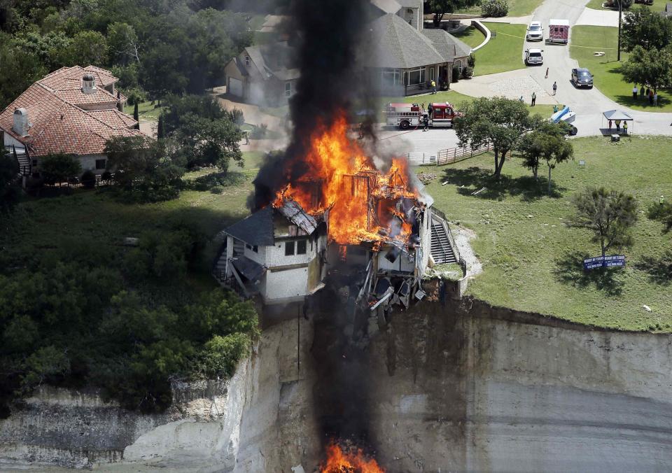 Smoke rises from a house deliberately set on fire, days after part of the ground it was resting on collapsed into Lake Whitney, Texas June 13, 2014. Building crews set fire on Friday to the luxury lake house left dangling about 75 feet (23 meters) on a decaying cliff that has been giving way underneath the structure. REUTERS/Brandon Wade (UNITED STATES - Tags: REAL ESTATE BUSINESS SOCIETY)