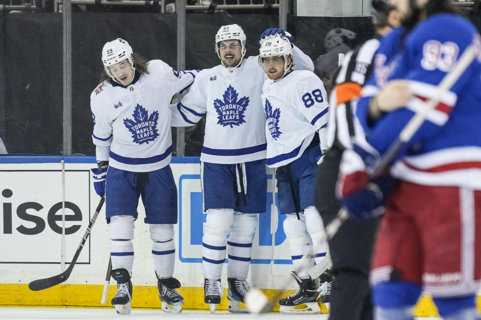 Toronto Maple Leafs' Auston Matthews, center, celebrates with teammates William Nylander (88) and Tyler Bertuzzi after scoring during the third period of an NHL hockey game against the New York Rangers, Tuesday, Dec. 12, 2023, in New York. (AP Photo/Seth Wenig)