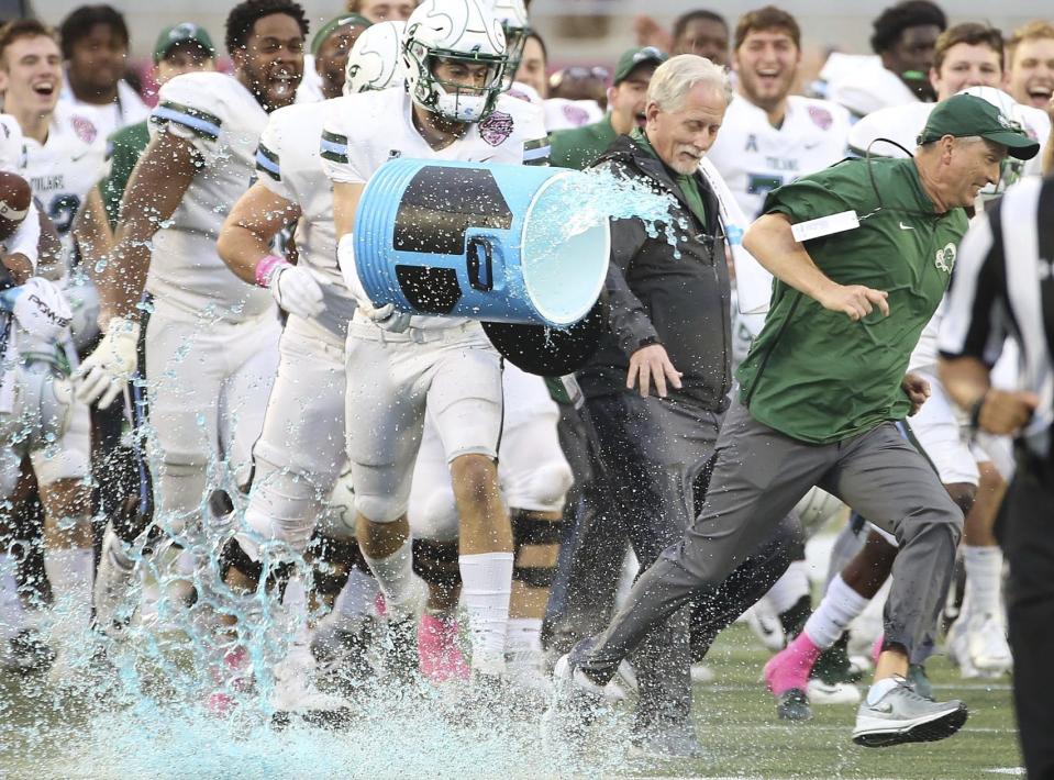 Tulane coach Willie Fritz, right, outruns the beverage shower as players celebrate after winning the Cure Bowl NCAA college football game against Louisiana in Orlando, Fla, on Saturday, Dec. 15, 2018. (Stephen M. Dowell/Orlando Sentinel via AP)