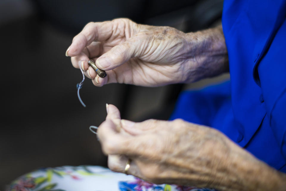 A woman holds her hearing aid as she visits Hear Again America for a checkup on Oct. 20, 2021 in Fort Lauderdale, Fla. (Joe Raedle / Getty Images file)