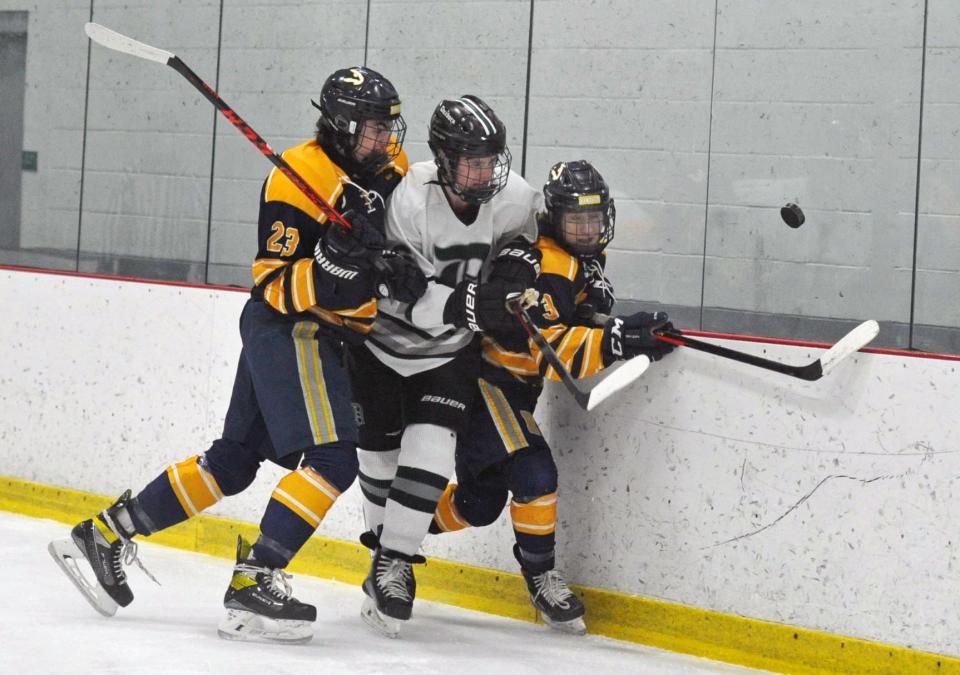 Duxbury's Connor O'Connell, center, is sandwiched by Hanover's  Justin Watson, left, and Max Dasilva as they battle along the boards for a loose puck during boys hockey at The Bog in Kingston on Monday, Jan. 31, 2022.