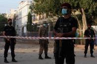 Police officers guard a cordoned-off street leading to the site of a passenger plane crash in a residential area near an airport in Karachi,