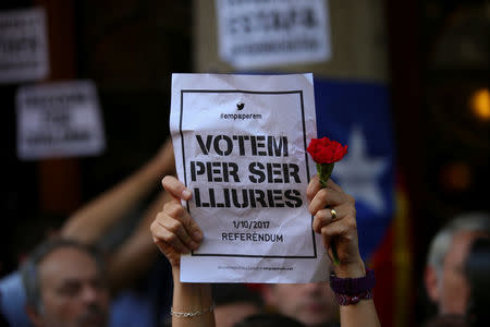 A protestor holds up a placard reading "We vote for being free" outside the Catalan region's economy ministry building during a raid by Spanish police on several government offices, in Barcelona, Spain, September 20, 2017. REUTERS/Albert Gea