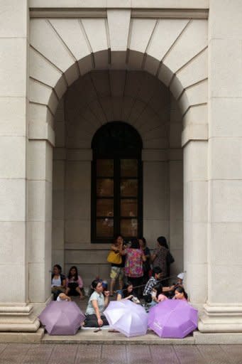 Foreign domestic helpers sit beneath the arches of the former Legislative Council building in Hong Kong on October 2. A court ruling has given them a chance to apply for permanent residency -- but the decision, which has polarised opinions in the southern Chinese city, has also prompted different reactions among maids themselves