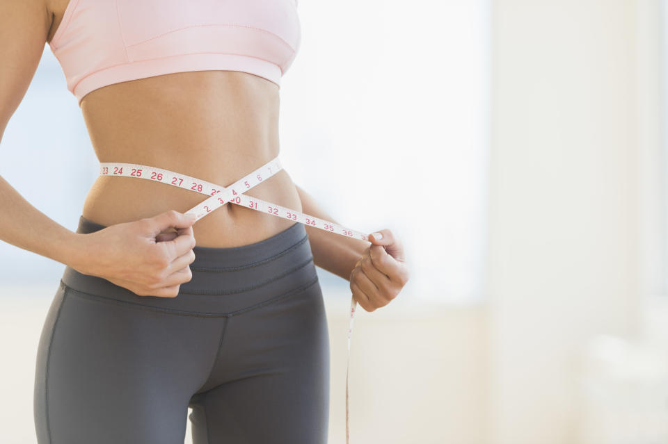 USA, New Jersey, Jersey City, Woman measuring waist