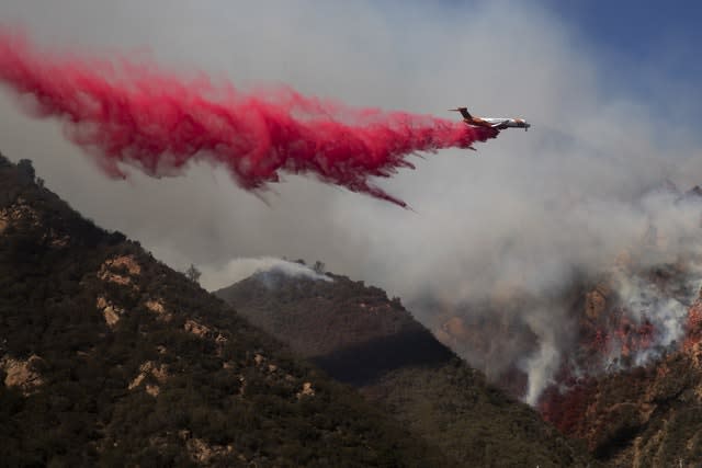 A plane drops fire retardant on a burning hillside in Malibu