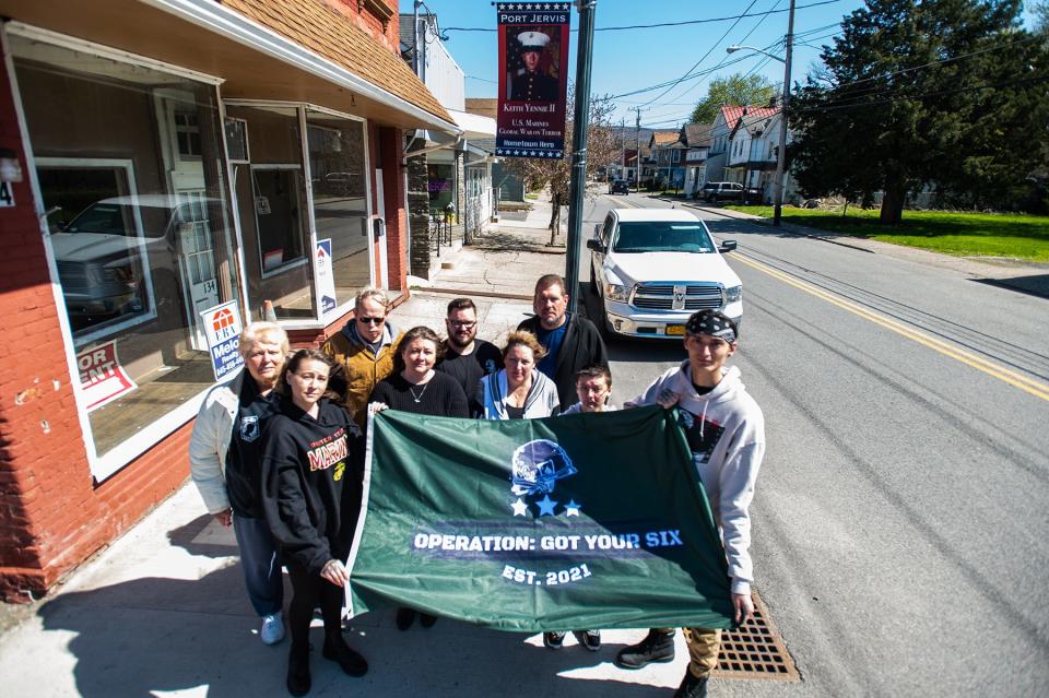 Family and friends stand below the Hometown Heroes banner featuring veteran Keith Yennie of Port Jervis on Jersey Avenue in Port Jervis on April 29, 2022.