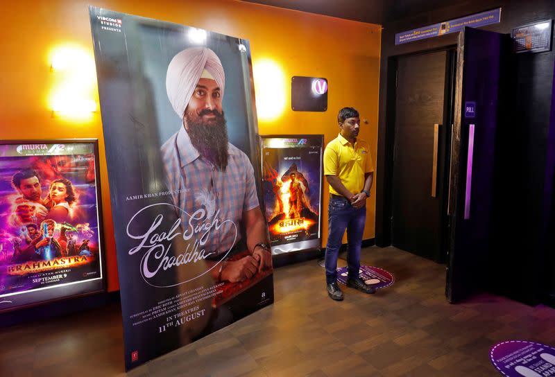 A ticket checker waits for film-goers at the gate of a cinema hall showcasing Aamir Khan-starrer "Laal Singh Chaddha" in Ahmedabad