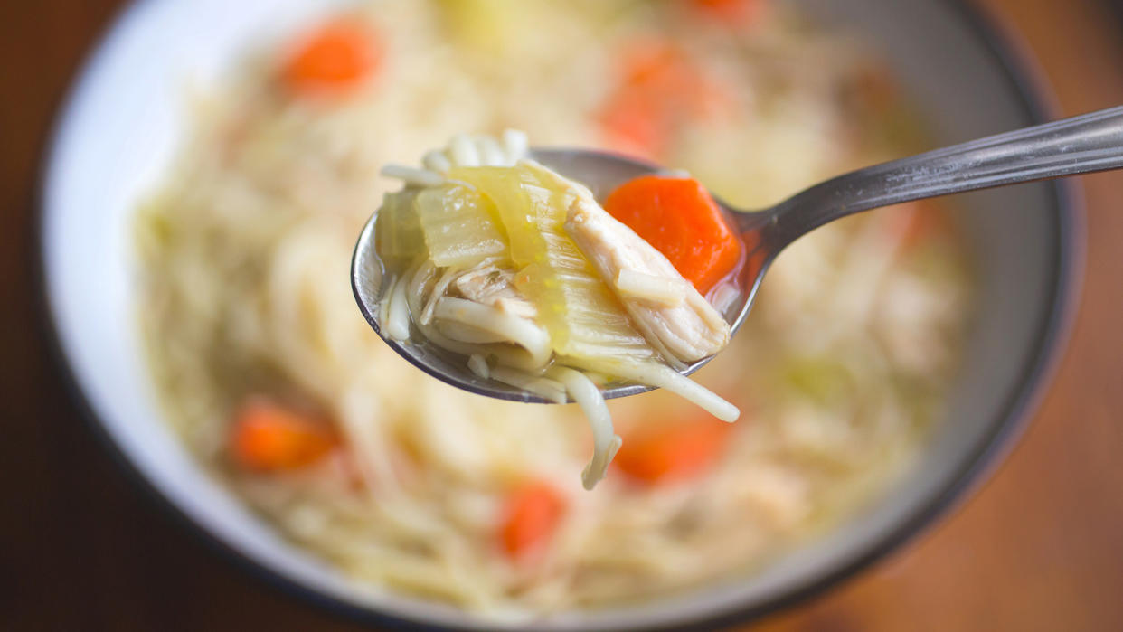 Bowl of chicken soup with a spoon directly above