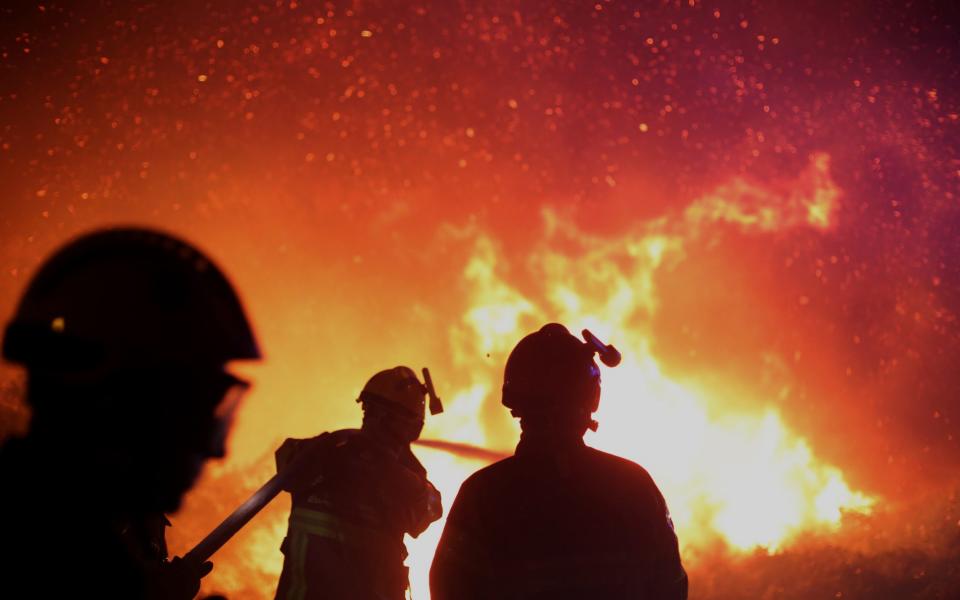 Firefighters spray water as they try to douse a fire near the village of Biguglia, Corsica island, France - Credit:  Raphael Poletti/ AP