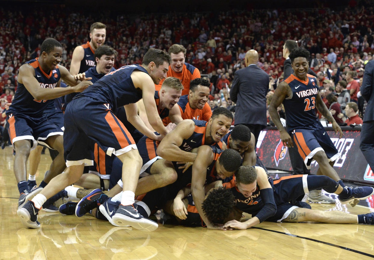 Teammates pile onto Virginia guard De’Andre Hunter (12) following his winning three-point basket at the buzzer to defeat Louisville in an NCAA college basketball game, Thursday, March 1, 2018, in Louisville, Ky. (AP Photo/Timothy D. Easley)