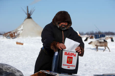 A herder of the agricultural cooperative organisation "Harp" casts his vote into a mobile ballot box during the early voting in remote areas ahead of the presidential election, at a reindeer camping ground, about 250 km south of Naryan-Mar, in Nenets Autonomous District, Russia, March 4, 2018. REUTERS/Sergei Karpukhin