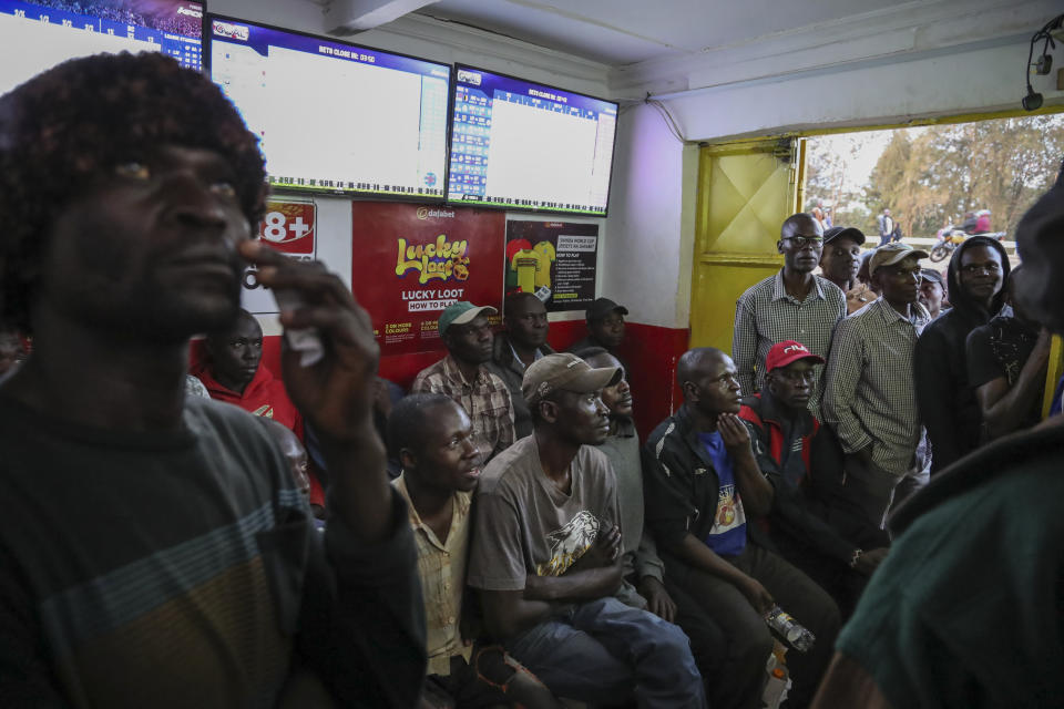 Customers watch screens in a sports betting shop in the low-income Kibera neighborhood of the capital Nairobi, Kenya, Monday, Dec. 5, 2022. Although sports betting is a global phenomenon and a legitimate business in many countries, the stakes are high on the continent of 1.3 billion people because of lax or non-existent regulation, poverty and widespread unemployment. (AP Photo/Brian Inganga)