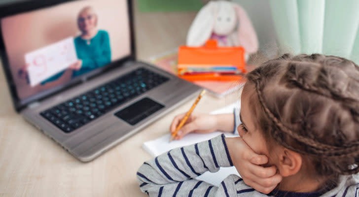 GNS stock: a child in front of a laptop taking notes while viewing an online class