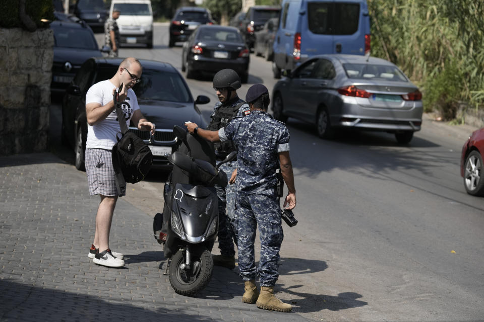 CORRECTS THE DETAIL OF THE PLACE - Lebanese soldiers check a motorcyclist's documents as investigators collect forensic evidence on a road leading to the U.S. Embassy in Aukar, a northern suburb of Beirut, Lebanon, Wednesday, June 5, 2024. The Lebanese army said Wednesday a gunman attempted to attack on the U.S. embassy near Beirut. (AP Photo/Bilal Hussein)
