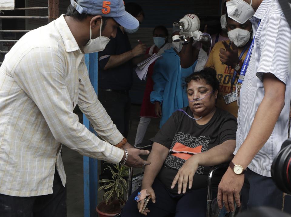 Health workers shift a patient after a fire in Vijay Vallabh COVID-19 hospital at Virar, near Mumbai, India, Friday, April 23, 2021. A fire killed 13 COVID-19 patients in a hospital in western India early Friday as an extreme surge in coronavirus infections leaves the nation short of medical care and oxygen. (AP Photo/Rajanish Kakade)