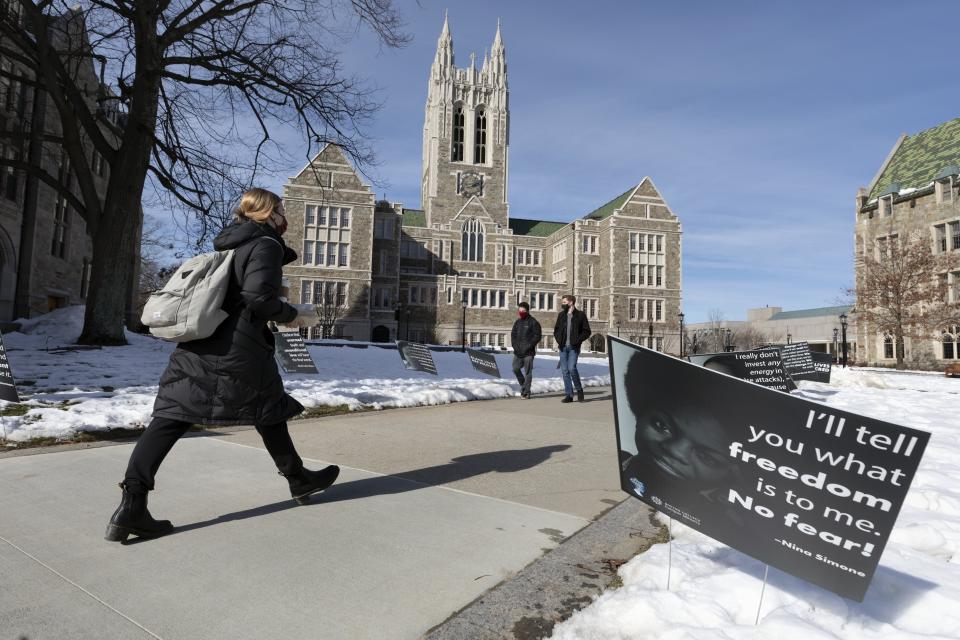 Students walk past Black History Month posters on the Boston College campus, Wednesday, Feb. 17, 2021, in Boston. Harassment by white male students targeting Black and Latina women housed in a Boston College dormitory has revived concerns about racism on campus. (AP Photo/Michael Dwyer)