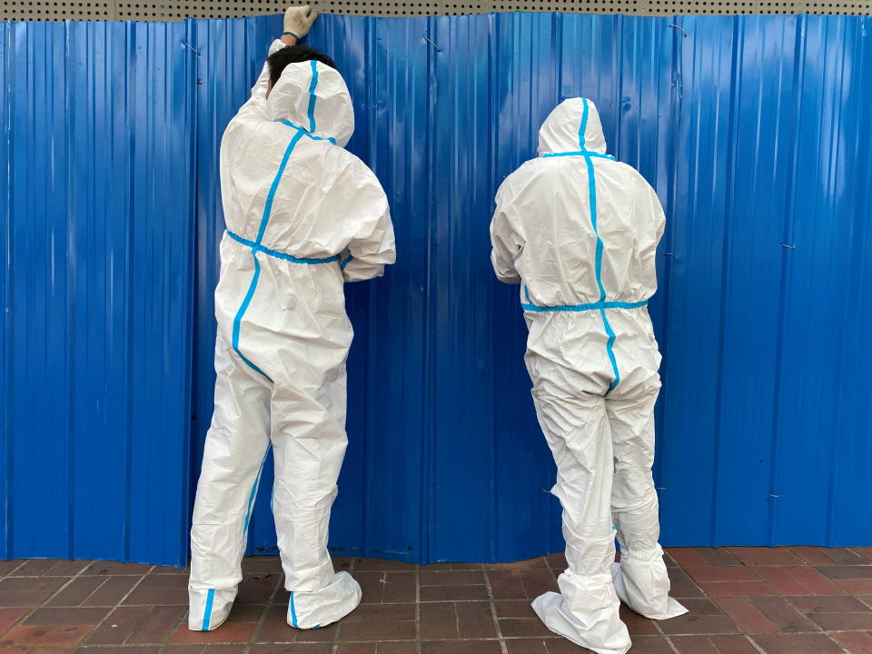 Workers in protective suits set up barriers outside a building, following the coronavirus disease (COVID-19) outbreak, in Shanghai, China June 9, 2022. REUTERS/Andrew Galbraith