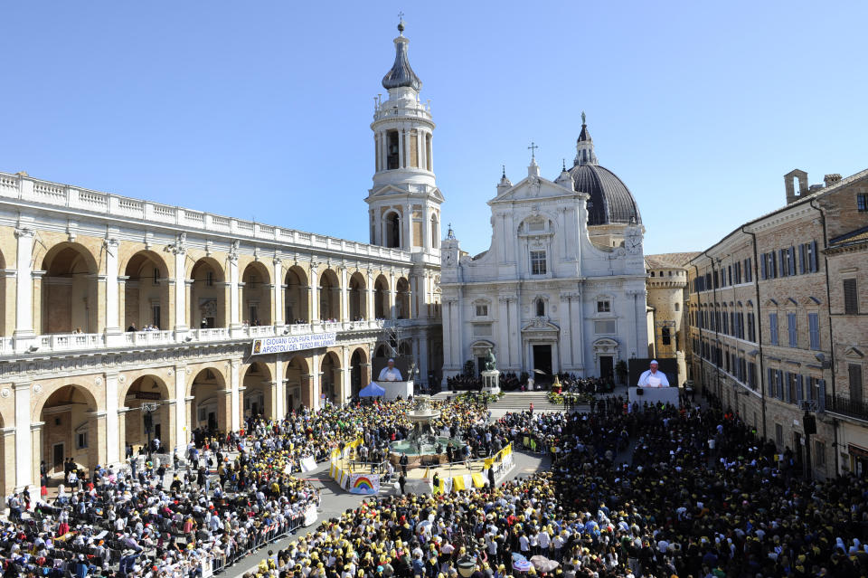 Pope Francis seen on a giant screen at right, celebrates Mass outside Loreto's cathedral, central Italy, Monday, March 25, 2019. Francis has traveled to a major Italian pilgrimage site dedicated to the Virgin Mary to sign a new document dedicated to today's youth. (AP Photo/Sandro Perozzi)