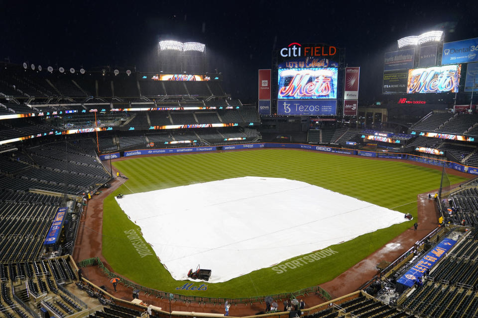 Security stands on the field as rain falls before a baseball game between the New York Yankees and the Baltimore Oriole, Monday, Oct. 3, 2022, in New York. (AP Photo/Frank Franklin II)