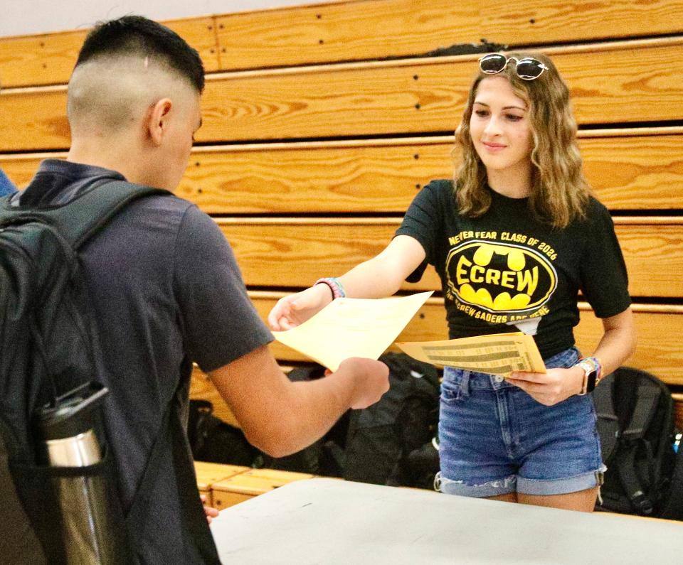 Enterprise High School junior Lauren Benson, right, hands a class schedule to a fellow student during the first day of school on Wednesday. Benson is an Ecrew member who helps out freshmen and other new students.