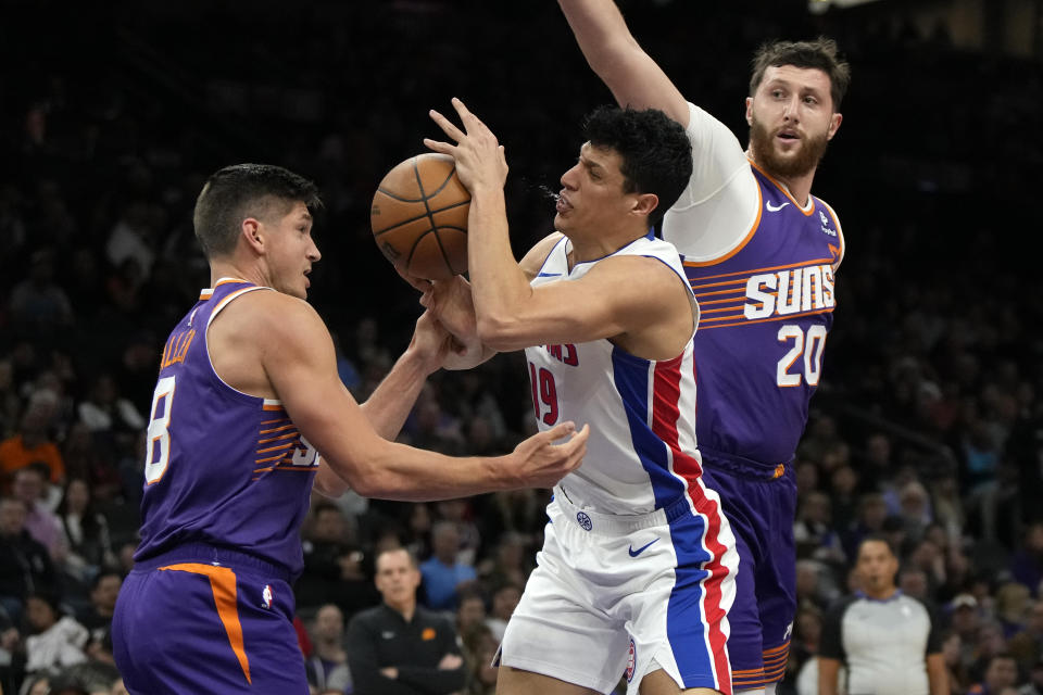 Detroit Pistons forward Simone Fontecchio drives between Phoenix Suns guard Grayson Allen and center Jusuf Nurkic (20) during the first half of an NBA basketball game, Wednesday, Feb. 14, 2024, in Phoenix. (AP Photo/Rick Scuteri)