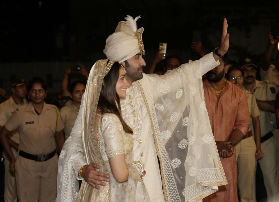 Bollywood actors Ranbir Kapoor, behind and Alia Bhatt pose for photographs after their wedding outside their residence in Mumbai, India, Thursday, April 14, 2022. (AP Photo/Rajanish Kakade)