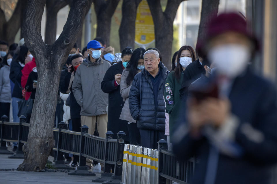 People wearing face masks stand in line for COVID-19 tests at a coronavirus testing site in Beijing, Tuesday, Nov. 15, 2022. The flagship newspaper of China's ruling Communist Party has called for strict adherence to the country's hardline "zero-COVID" policy, in an apparent attempt to guide public perceptions following a slight loosening of anti-virus regulations. (AP Photo/Mark Schiefelbein)