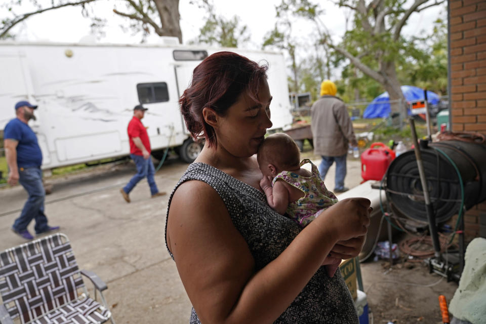 Hannah Bourque holds one of her two-week old twins outside the camper she is living in with her grandfather, while her mother lives in a tent in the backyard, outside their heavily damaged home in the aftermath of Hurricane Laura and Hurricane Delta, in Lake Charles, La., Friday, Dec. 4, 2020. (AP Photo/Gerald Herbert)